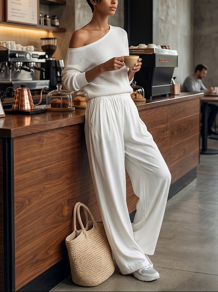 A woman wearing the Adele Bennett and Lowe two-piece set with a one-shoulder top and wide-leg pants in a stylish indoor setting.