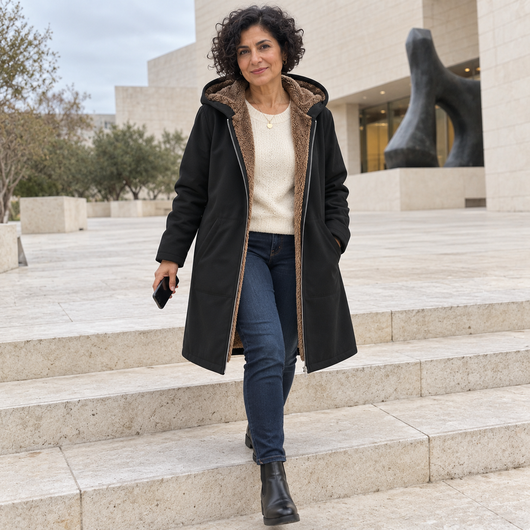 Heather Bennett & Lowe hooded longline winter coat displayed in a museum courtyard, showcasing its stylish design and cozy fabric.