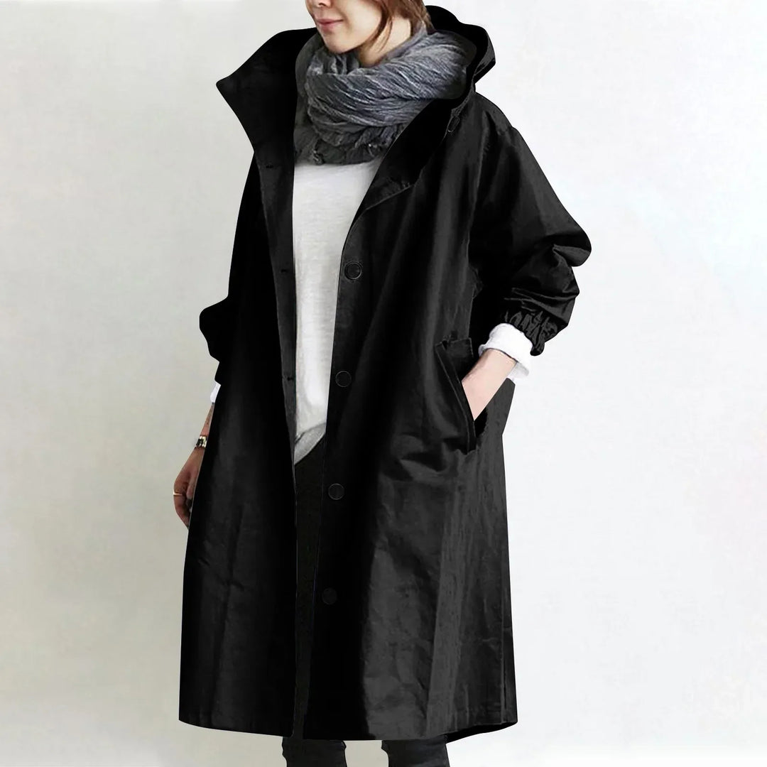 Eloise hooded longline trench coat by Bennett and Lowe, beige with belt, shown hanging on a wooden background.