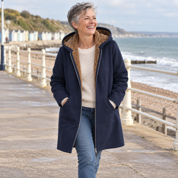Woman wearing Bennett & Lowe Heather hooded longline coat with sherpa lining at the seaside.