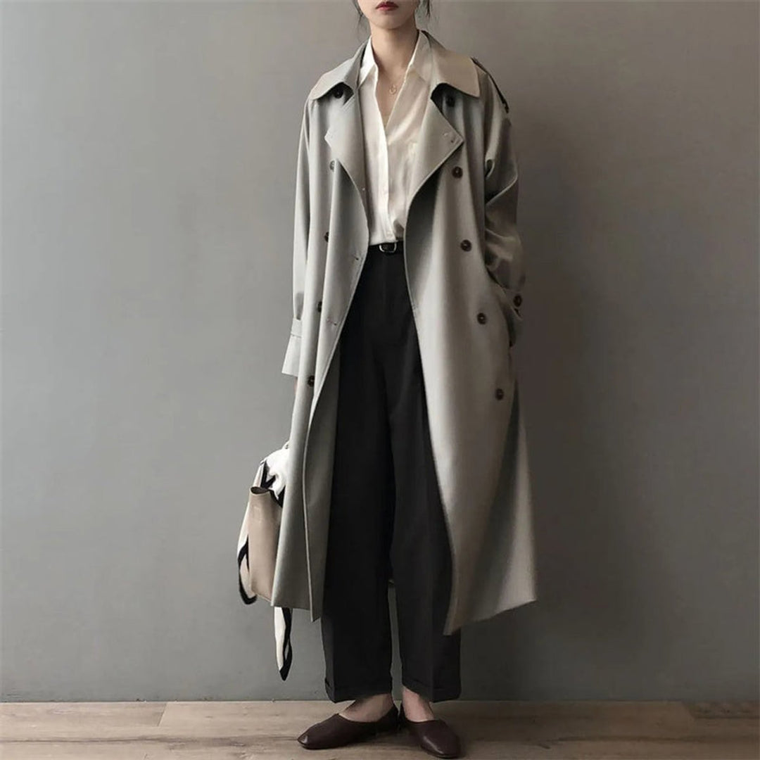 Women’s double-breasted Bennett and Lowe long trench coat with belt, water-repellent fabric, shown in a stylish outdoor setting.